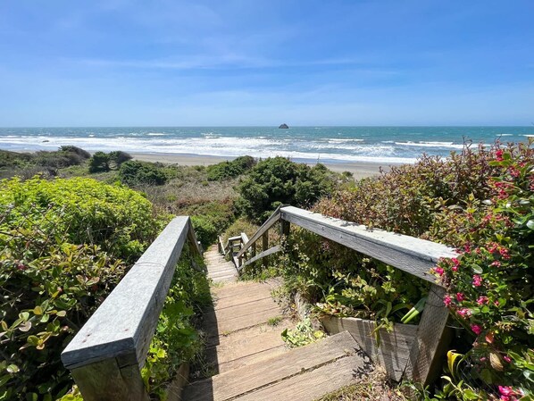 A wooden staircase leading to a beach with ocean views.