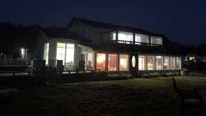Een gebouw met twee verdiepingen, grote ramen, een terras en een gazon.