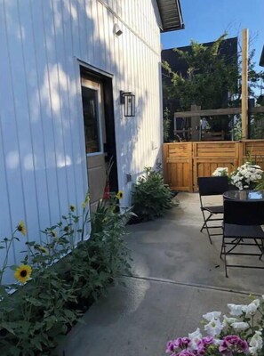 Un patio con piso de concreto, cerca de madera y una mesa con sillas.