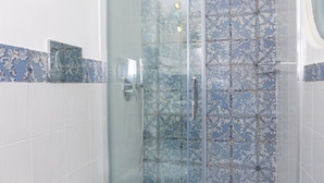 A bathroom with a glass shower enclosure and patterned tiles. - VRBO (Anacapri)