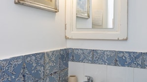 A bathroom with a patterned blue and white tile backsplash, a white sink, and a mirror above the sink. - VRBO (Anacapri)