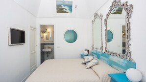 A bedroom with a large bed, two round mirrors, a TV, and a bathroom visible through an open door. - VRBO (Anacapri)