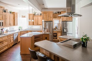 Une cuisine spacieuse dotée de meubles en bois, d’appareils électroménagers en acier inoxydable et d’un îlot central.