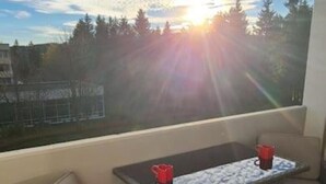 En balkong med möbler av rotting, ett bord och två röda muggar.