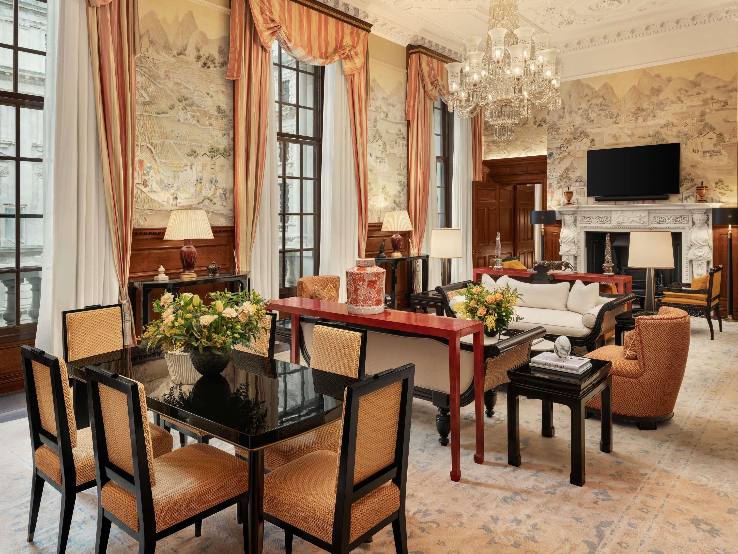 Een ruime woonkamer met een open haard, een eethoek met een glazen tafel en een zithoek met een bank en stoelen.