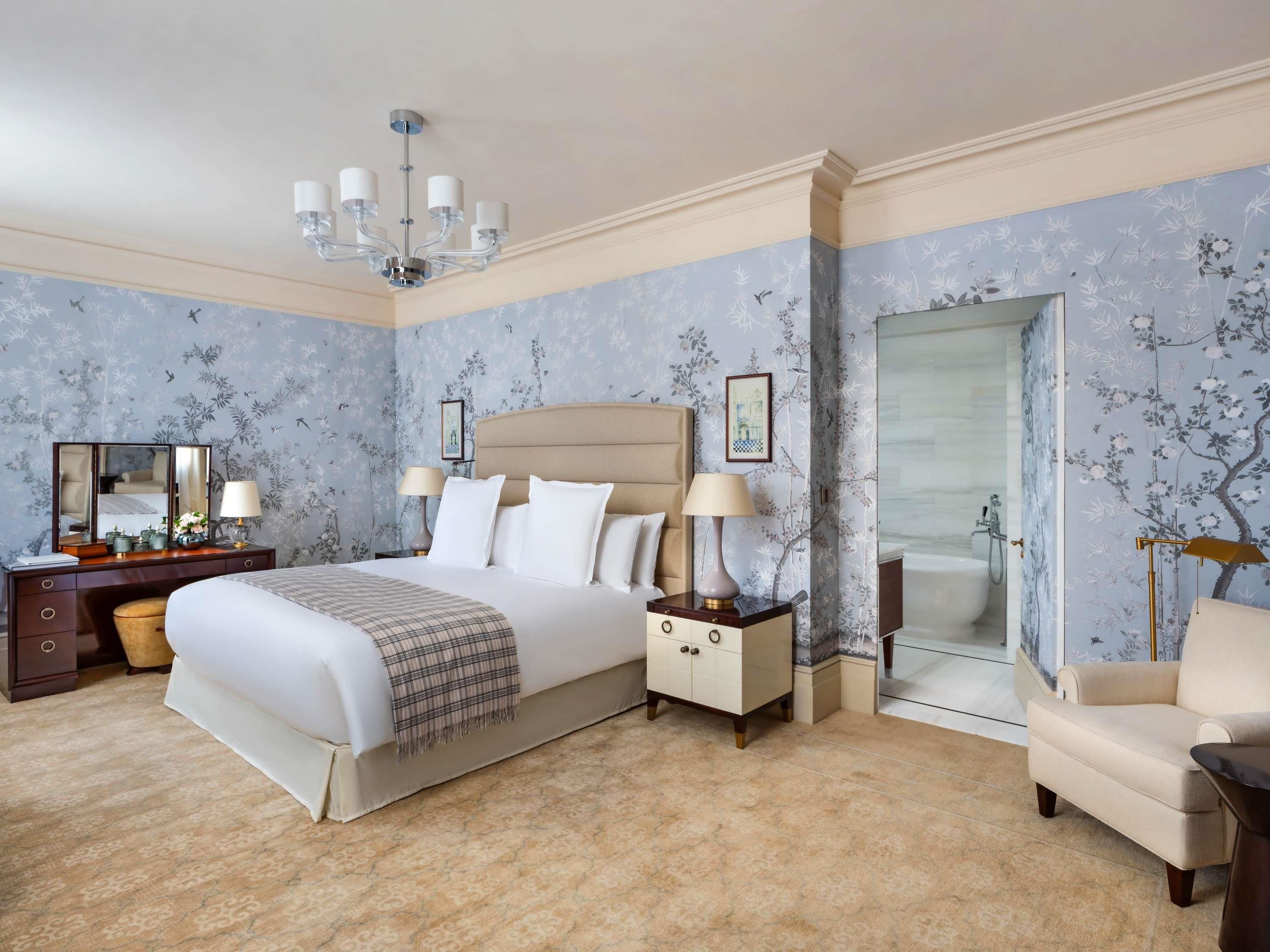A bedroom with a large bed, bedside tables, a dresser, a chair, and a bathroom with a bathtub.
