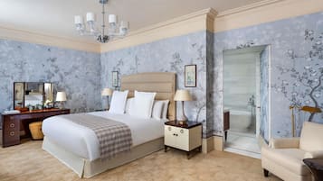 A bedroom with a large bed, bedside tables, a dresser, a chair, and a bathroom with a bathtub.