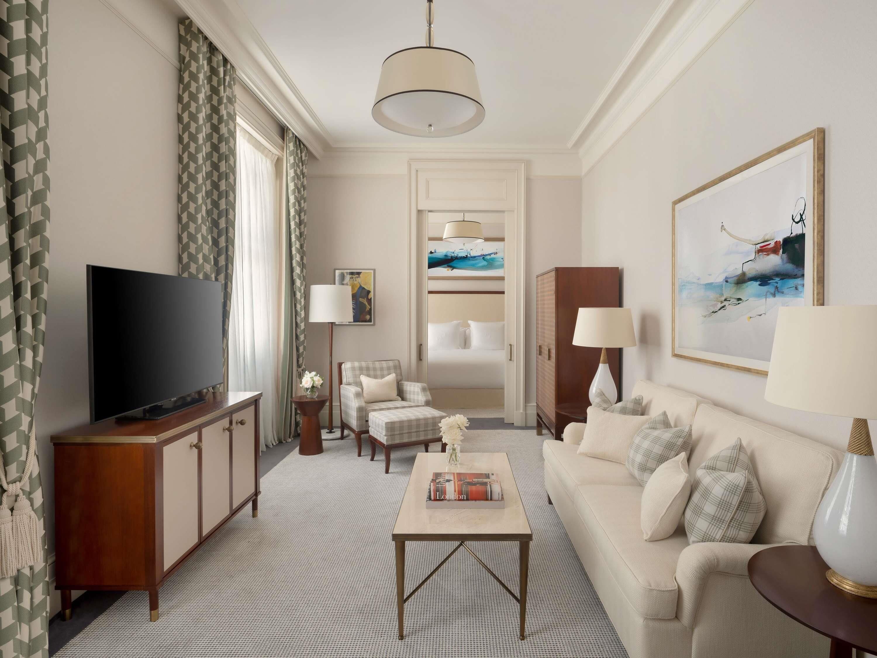 Une chambre d’hôtel moderne équipée d’un téléviseur à écran plat, d’un canapé, d’une table basse, d’une armoire, d’une lampe et d’un tableau au mur.
