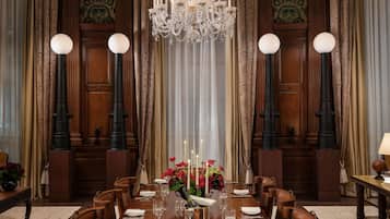 A formal dining room with a chandelier, curtains, and a table set for six.