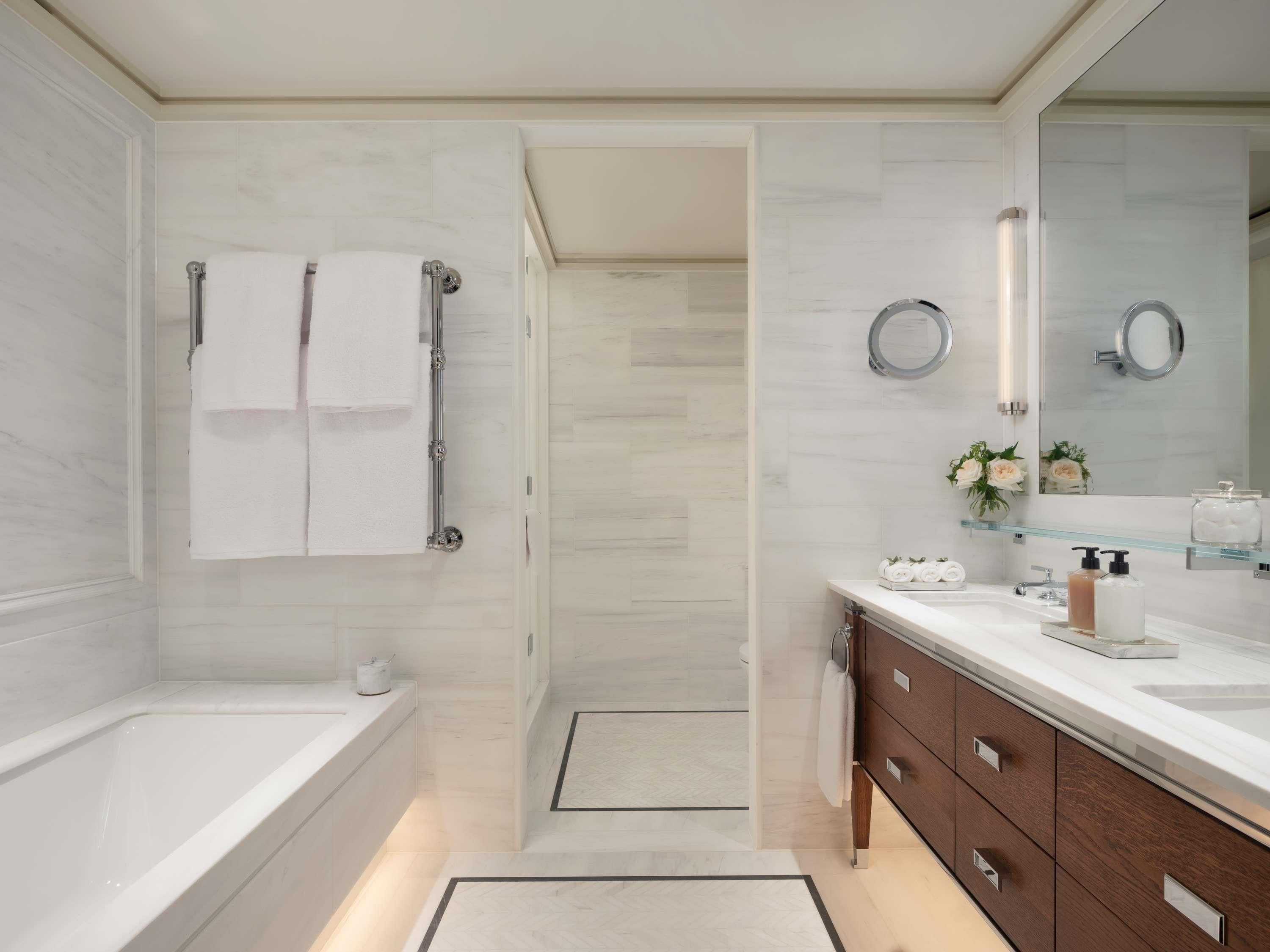 A modern bathroom with a bathtub, a glass shower enclosure, a vanity with a mirror, and a toilet.