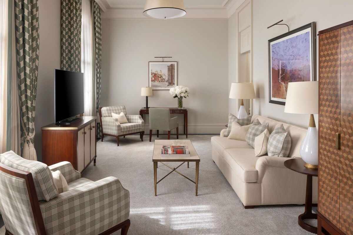 A living room with a television, two armchairs, a sofa, a coffee table, and a lamp.