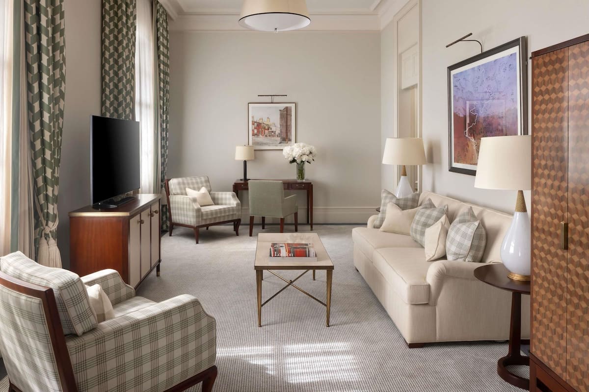 A living room with a television, two armchairs, a sofa, a coffee table, and a lamp.