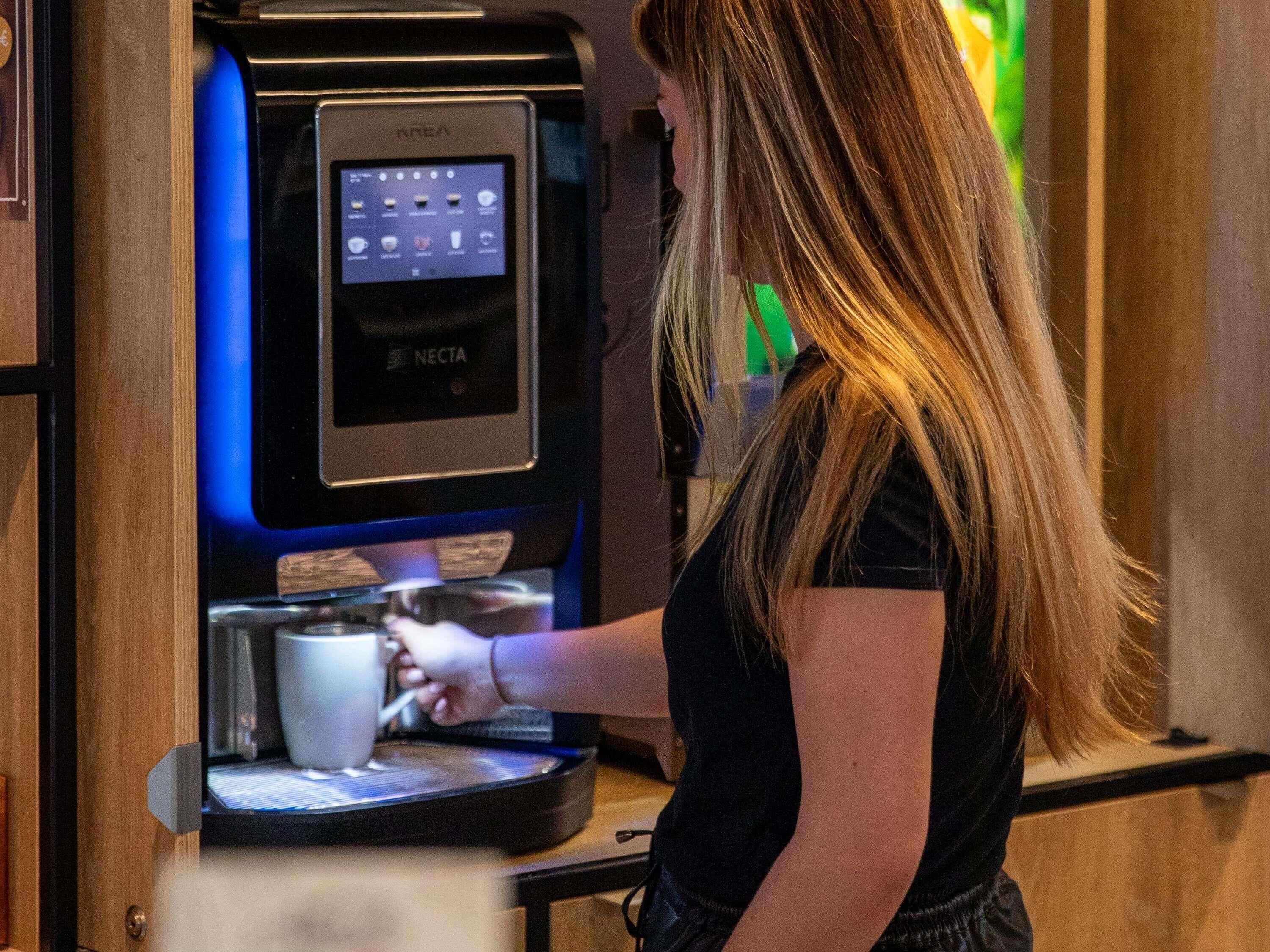 Una persona usando una máquina de café con pantalla digital.