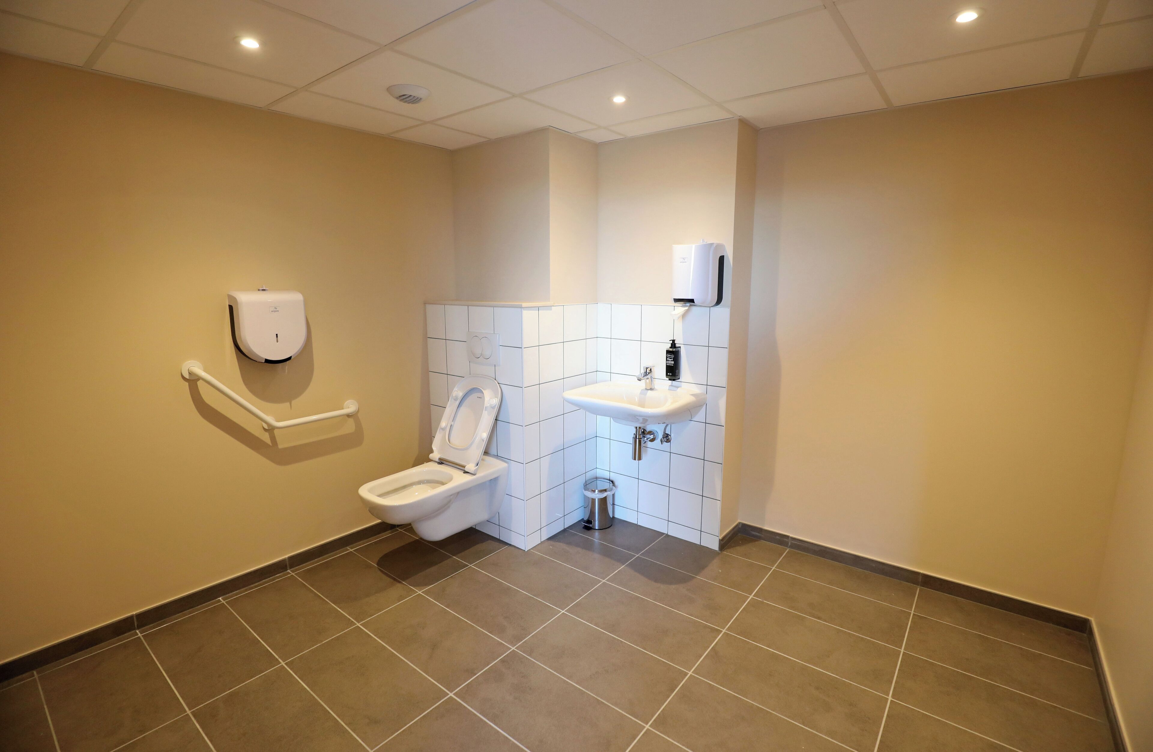 A modern bathroom with a toilet, hand dryer, and sink.