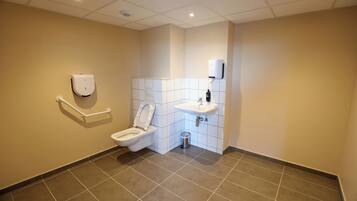 A modern bathroom with a toilet, hand dryer, and sink.