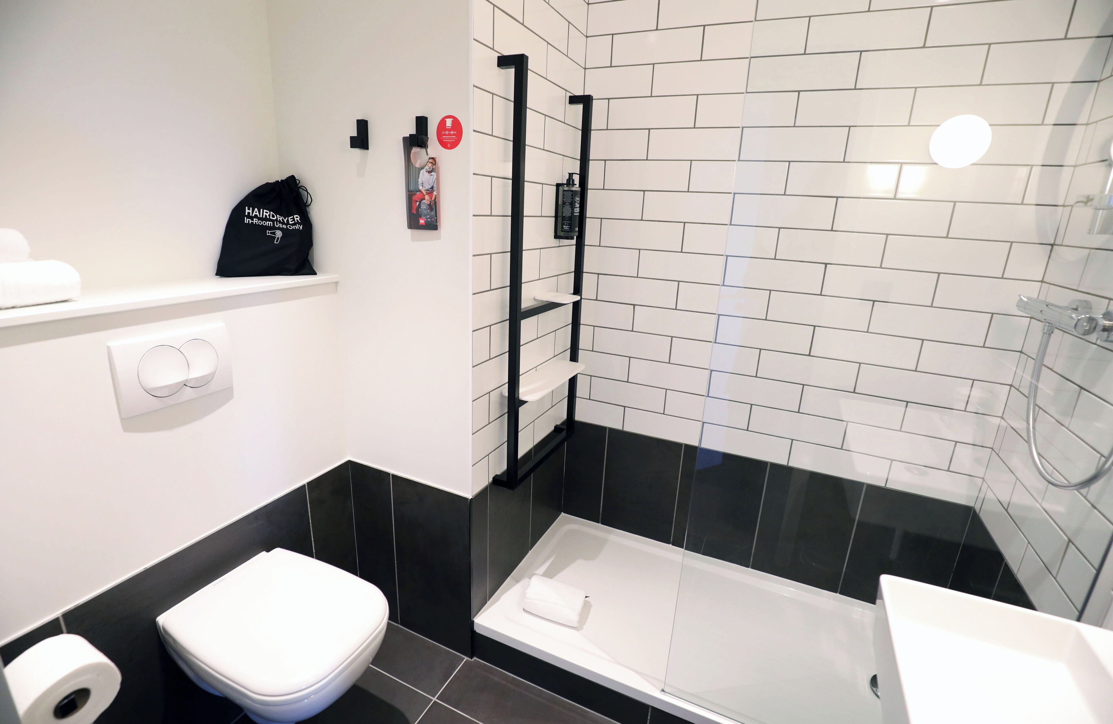 A modern bathroom with a white toilet, a black sink, and a glass-enclosed shower area.