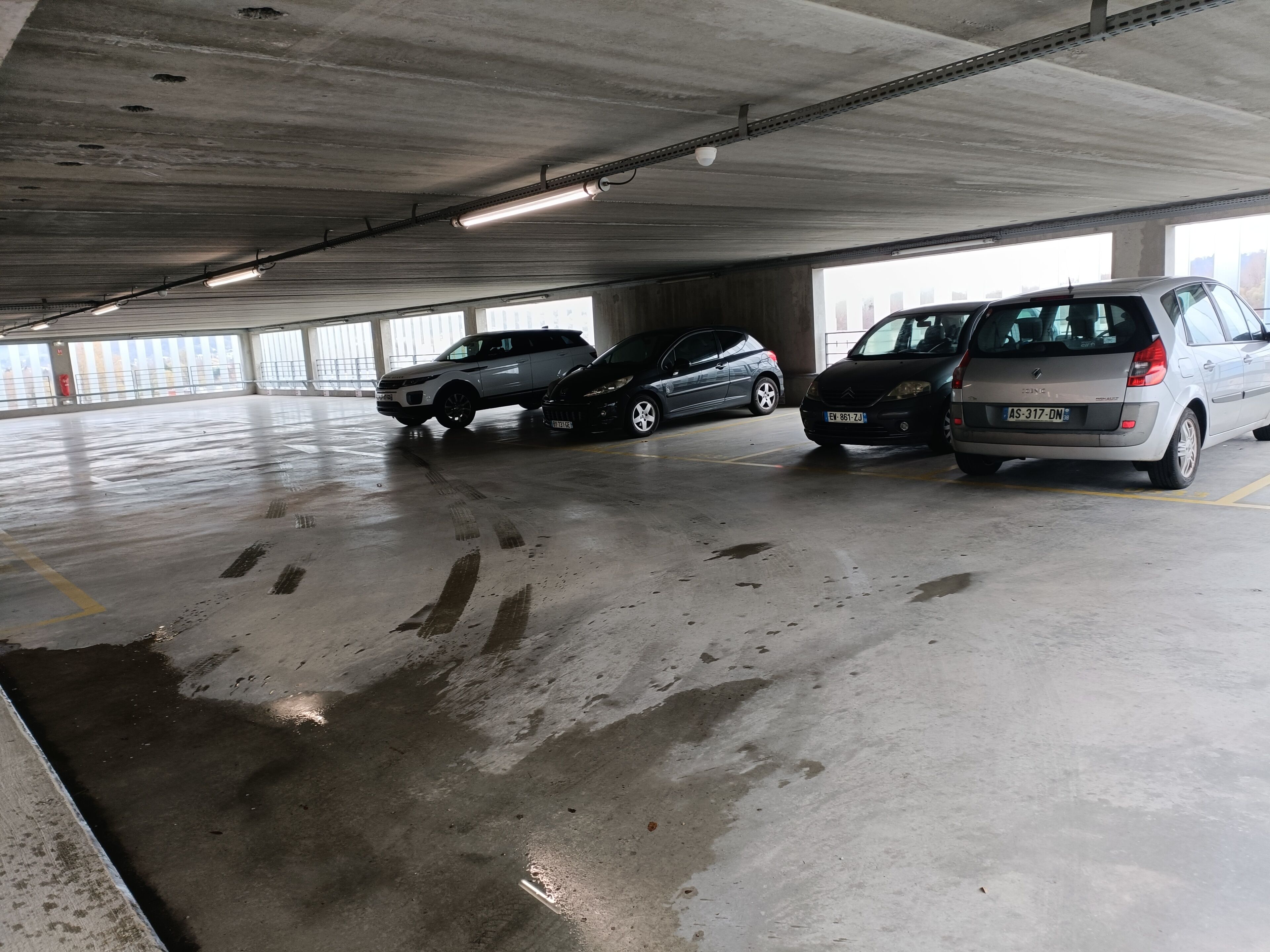 Un parking où trois voitures sont garées à la suite.