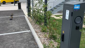 Pysäköintialue, jossa on keltainen kuorma-auto, huoltorasia ja portaikko, joka johtaa rakennukseen.