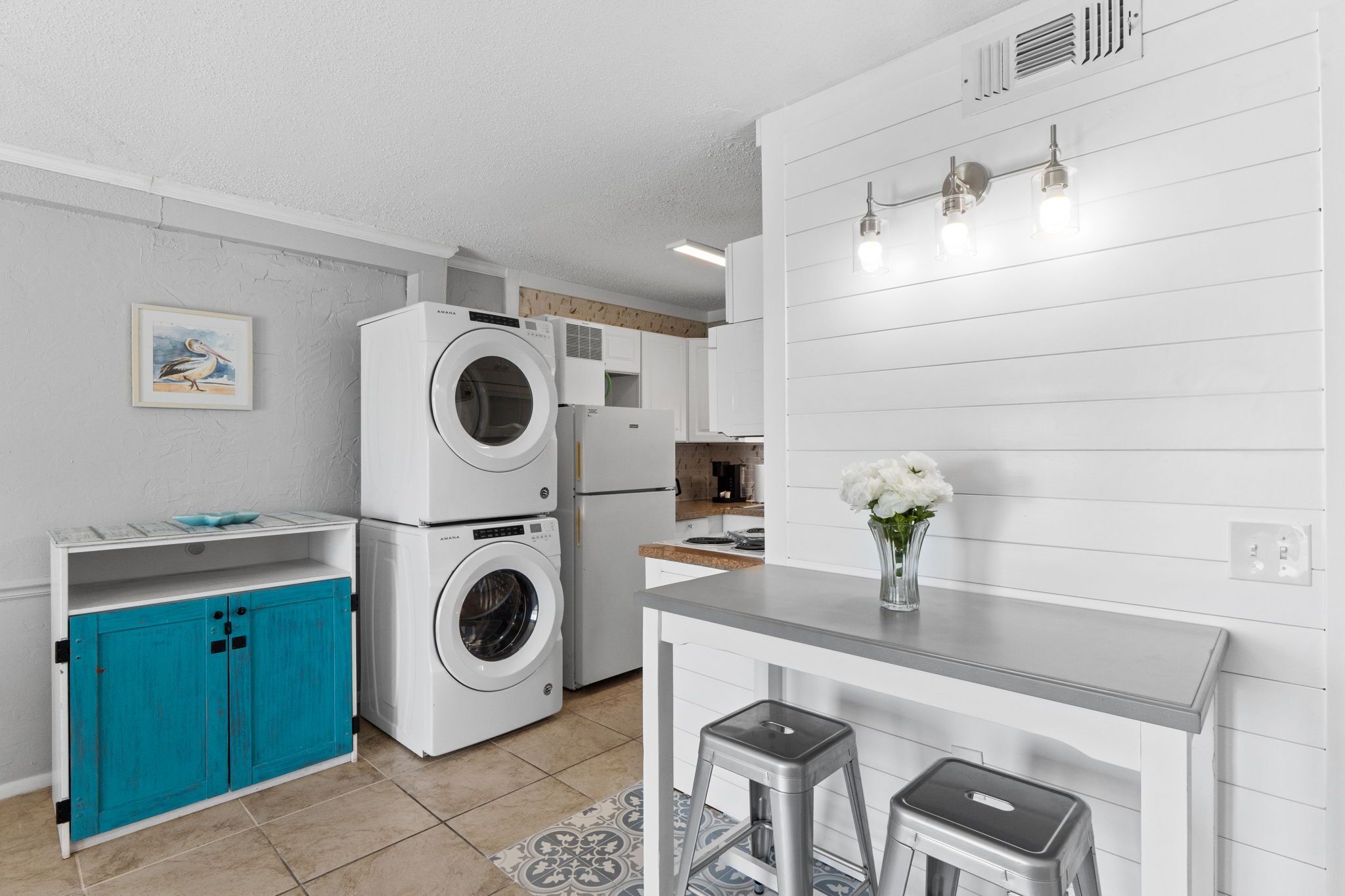 A compact kitchen with a washing machine, a small dining area, and a teal cabinet.