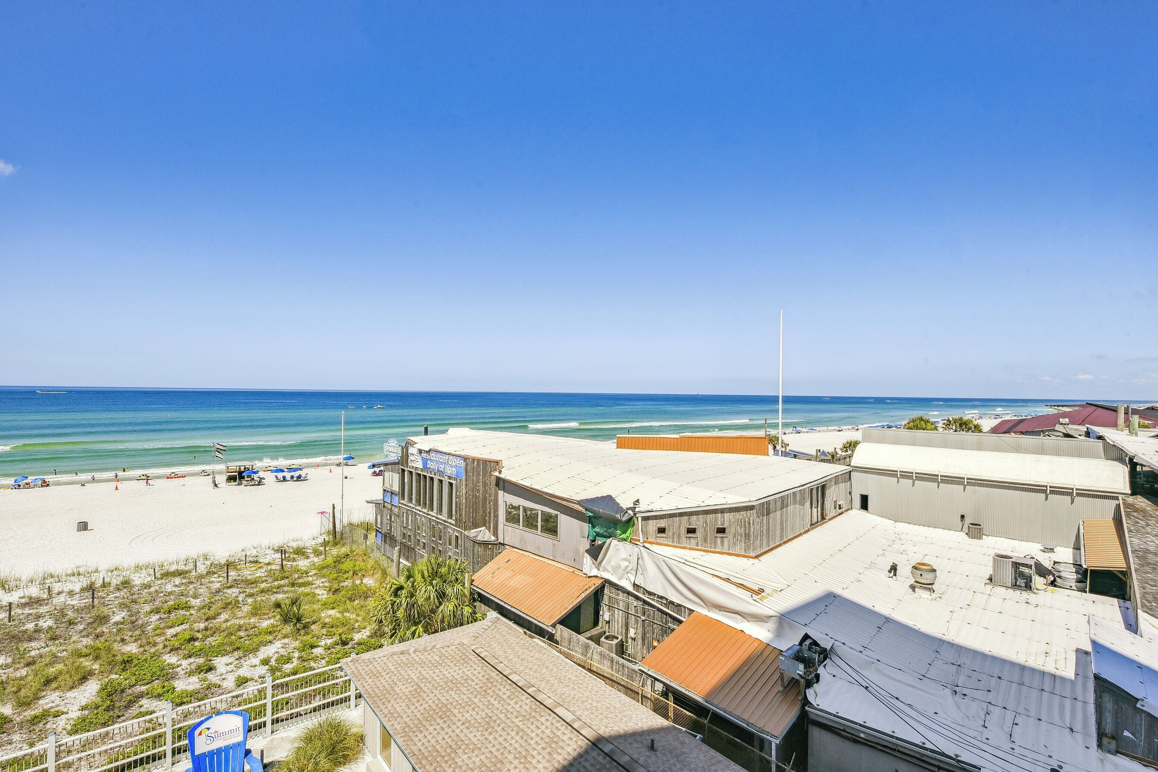 A beachside hotel with multiple buildings, a sandy beach, and the ocean in the background.