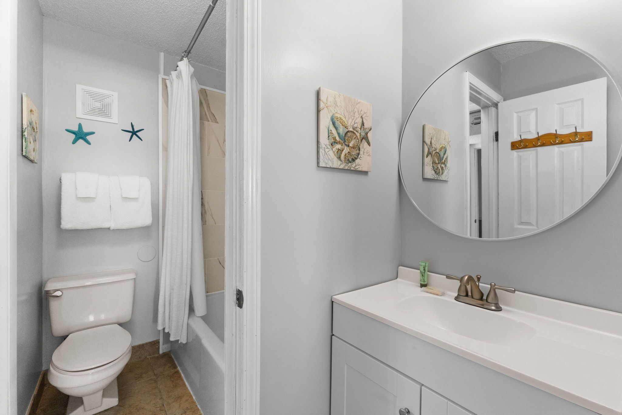 Une salle de bain équipée de toilettes, d’un lavabo, d’un miroir et d’un rideau de douche.
