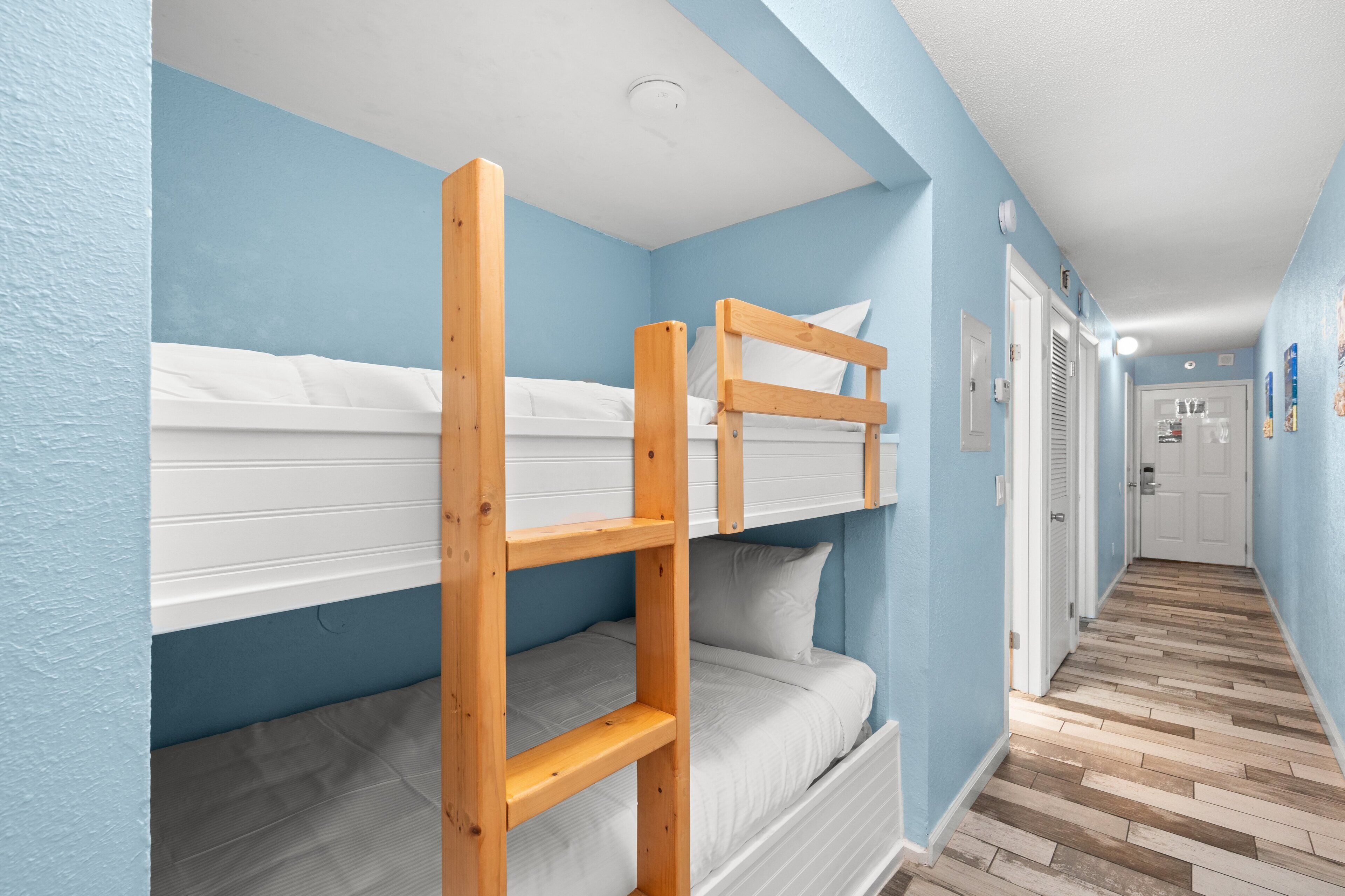 A bunk bed room with blue walls and a wooden floor.