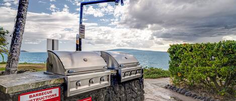 A barbecue grill with instructions, set against a scenic view of the ocean and a cloudy sky.