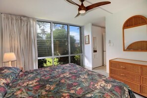 Relax in this serene bedroom with a large bed, ceiling fan, and a dresser with a mirror.