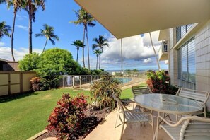Relax on the patio with a round table and two chairs, overlooking a well-maintained lawn and pool.