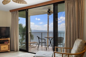 Un balcon avec vue sur la mer, une télévision et un coin salon avec une table et des chaises.