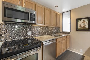 A kitchen with stainless steel appliances, wooden cabinets, and a tiled backsplash. - Wailea Elua, #2101 1 Bedroom Condo by RedAwning (Kihei)
