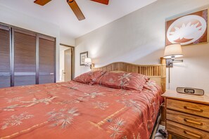 Ein Schlafzimmer mit einem Bett, Nachttischlampen, einem Nachttisch, einer Uhr und einem Deckenventilator.