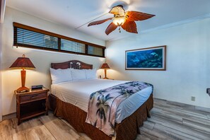 A bedroom with a bed, two bedside lamps, a ceiling fan, a window with blinds, and a framed picture on the wall. - Sugar Beach Resort, #414^ 1 Bedroom Condo by RedAwning (Kihei)