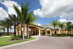 A hotel with a central courtyard, palm trees, and a tiled walkway. - Casa Palmero 5 Bedroom Home by RedAwning (Kissimmee)