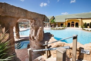 A pool area with a rock formation and a sign prohibiting climbing on rocks. - Casa Palmero 5 Bedroom Home by RedAwning (Kissimmee)