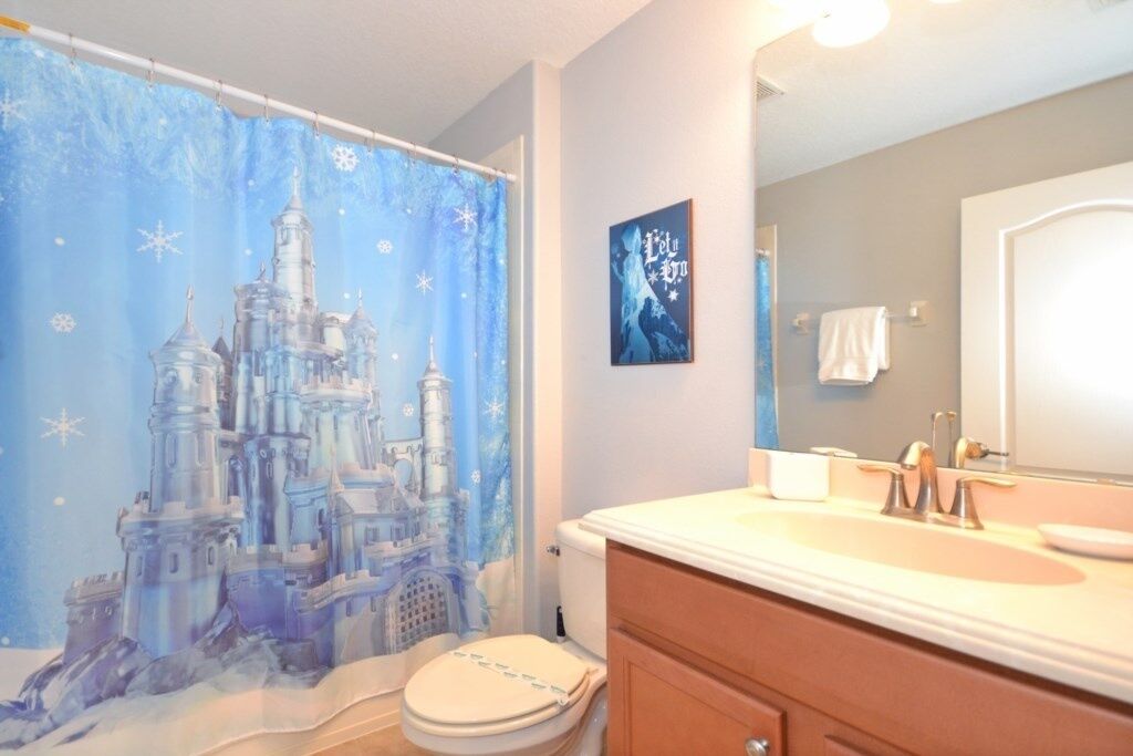 A bathroom with a castle-themed shower curtain, a sink, and a mirror.