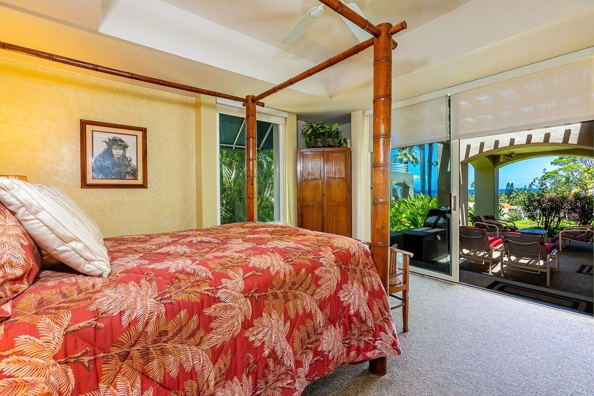 A bedroom with a four-poster bed, a large window, and a view of the outdoors.
