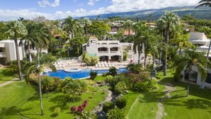 Et resort med en swimmingpool omgivet af palmer og frodig vegetation.