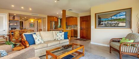A spacious living area with a high ceiling fan, a dining area with a view, and a kitchen with wooden cabinets.