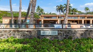 A hotel with a stone wall and a sign reading "WAILEA ELUA". - Wailea Elua by Coldwell Banker Island Vacations (Kihei)