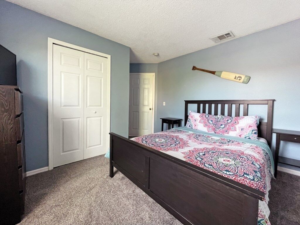 A bedroom with a wooden bed, a white door, and a baseball bat hanging on the wall.
