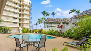 A hotel with a swimming pool, outdoor seating, and a multi-story building with balconies. - Big Island Kona Ali'i by Coldwell Banker Island Vacations (Kailua-Kona)