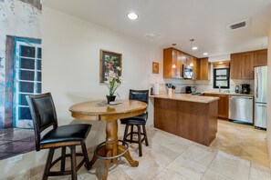 Una cocina con armarios de madera, un refrigerador de acero inoxidable y un comedor con una mesa redonda y sillas.