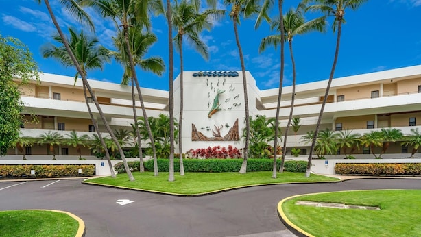 A hotel with a central atrium, palm trees, and a large mural.