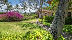 A well-maintained garden with a pathway leading to a building with a tiled roof. - Kauai Makanui by Coldwell Banker Island Vacations (Koloa)