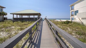 A wooden boardwalk leading to a beach with a gazebo and a building on the right. - Sweet Spot - Newly Renovated, Heated Pool, Golf Cart, Deeded Beach Access! (Miramar Beach)