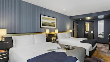 A hotel room with two beds, a large framed picture on the wall, and a bathroom visible through an open door.