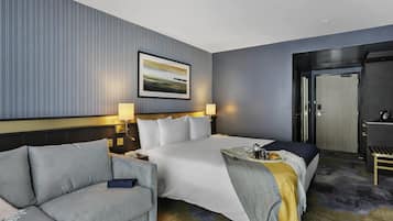 A hotel room with a large bed, a sofa, a desk, and a door.
