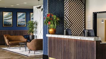 A reception area with a wooden reception desk, a brown leather sofa, and two framed artworks on the wall.