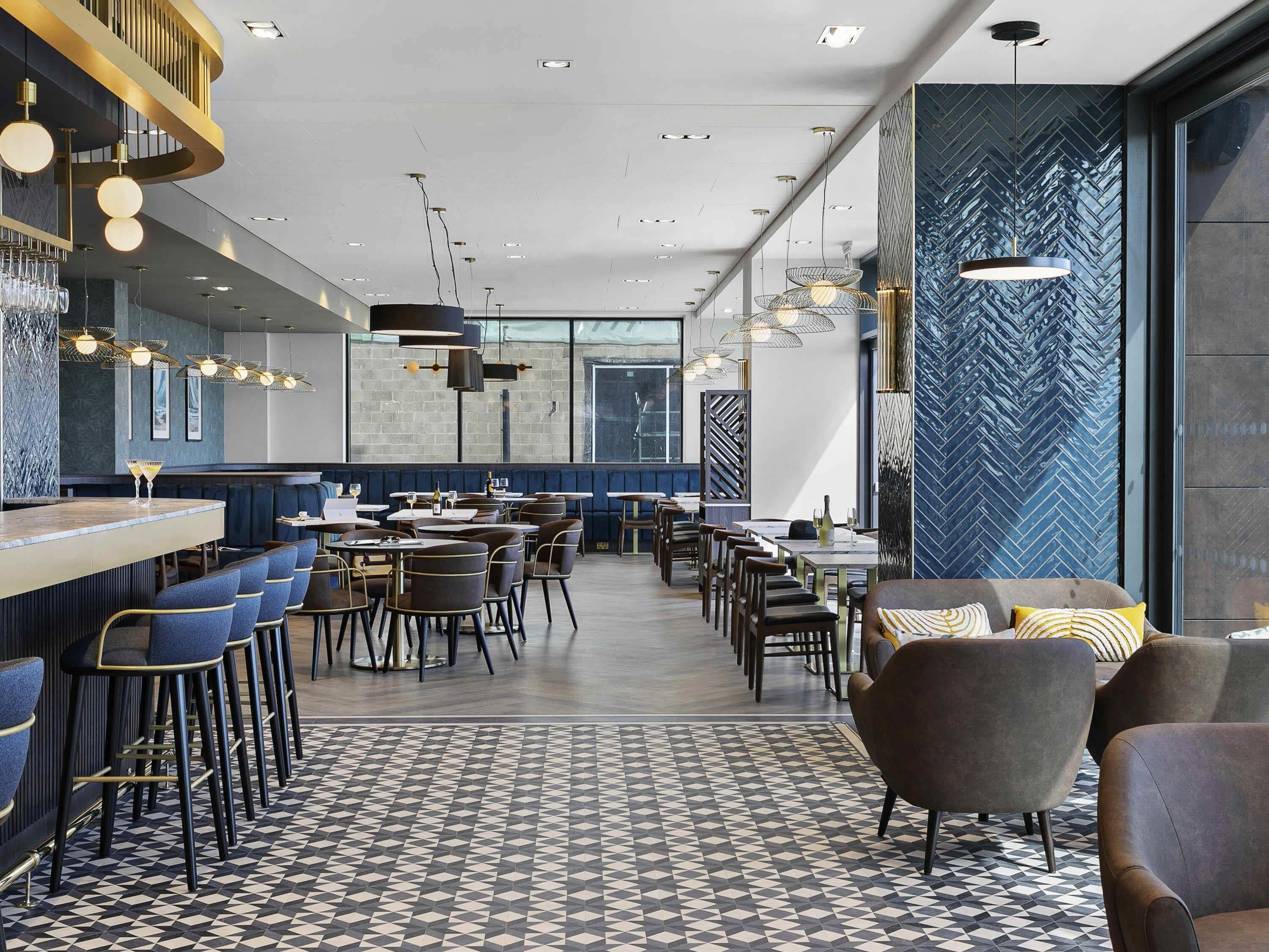 A modern restaurant with a bar area, dining tables, and chairs.